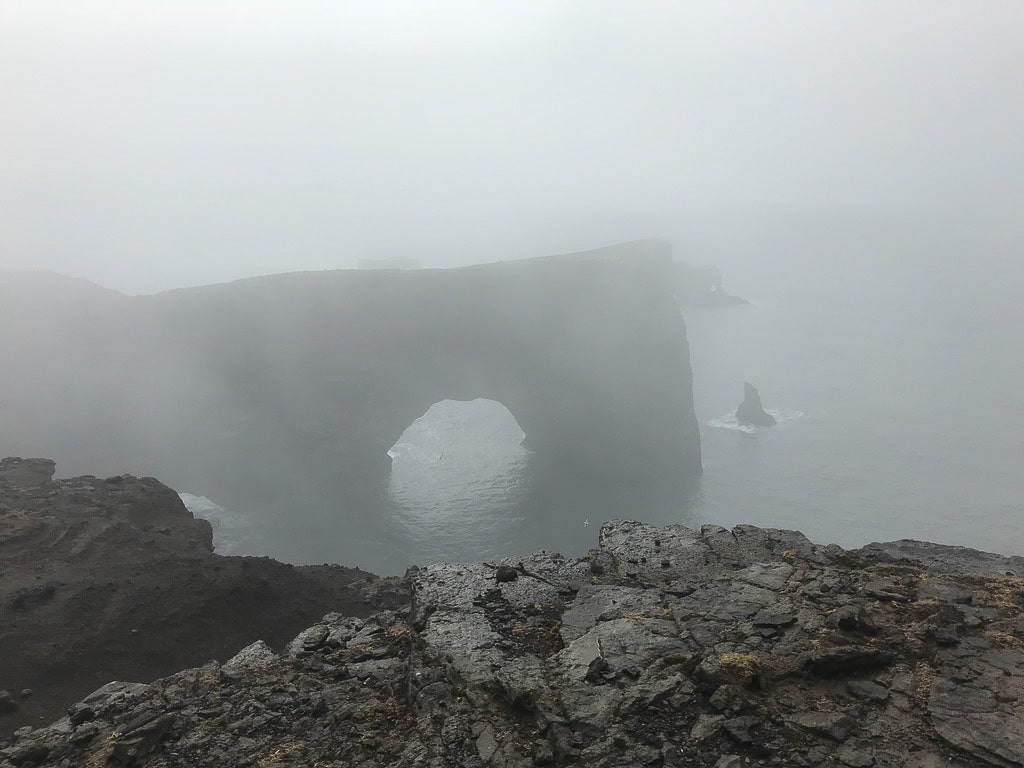Formation rocheuse Dyrhólaey dans le sud de l'Islande avec du brouillard